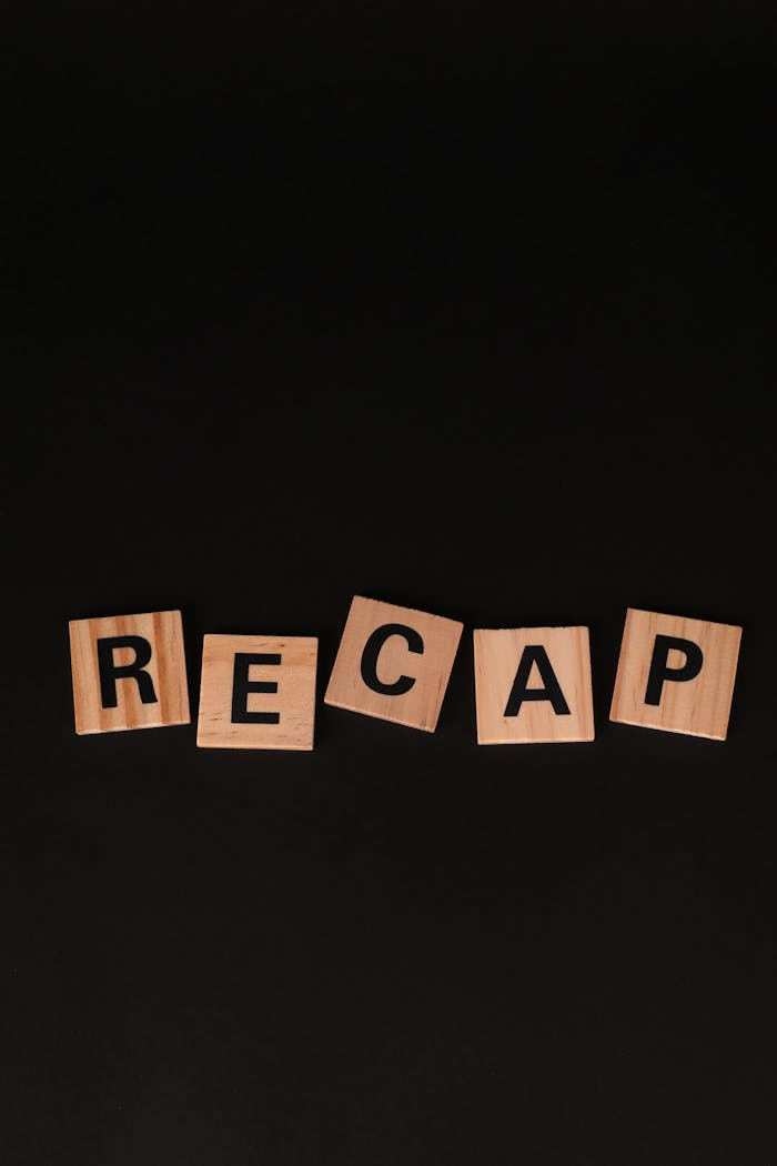 Services Scrabble-like wooden letter tiles forming the word 'RECAP' on a black background.